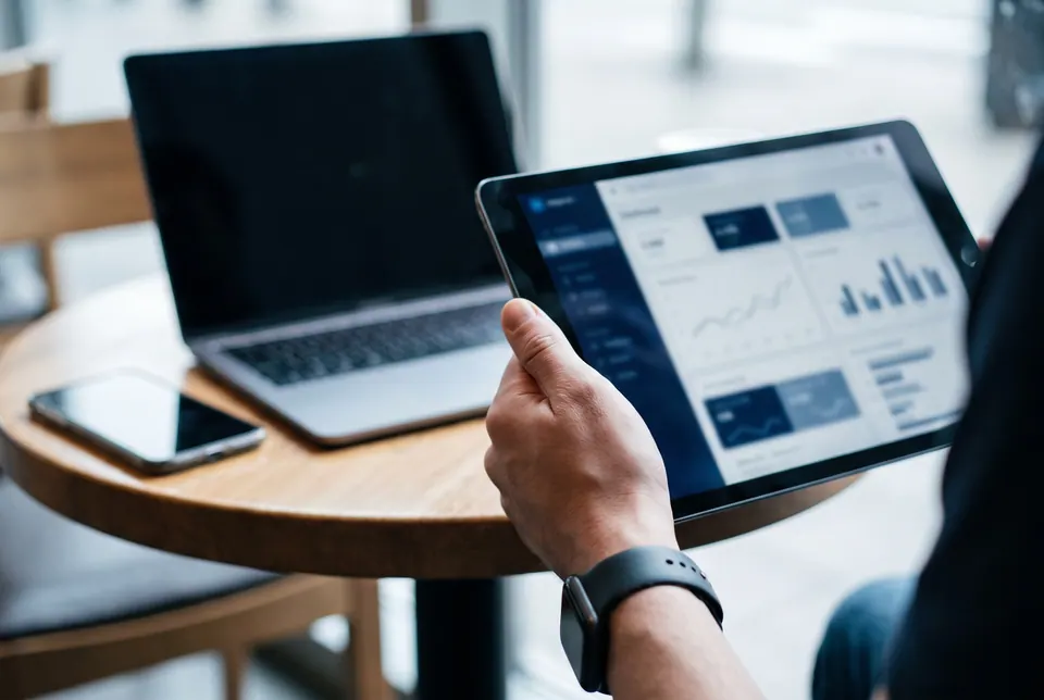 Hand hält ein Tablet mit einer Buchhaltungsoberfläche