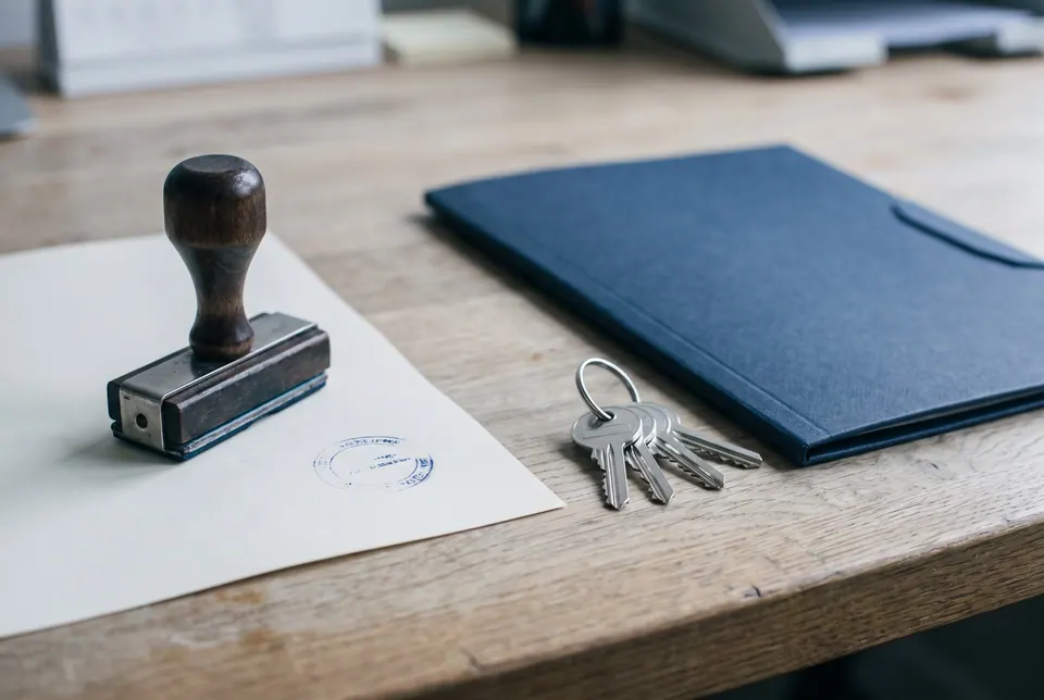 Firmenstempel neben einem gestempelten Dokument, Schlüsseln und Ordner