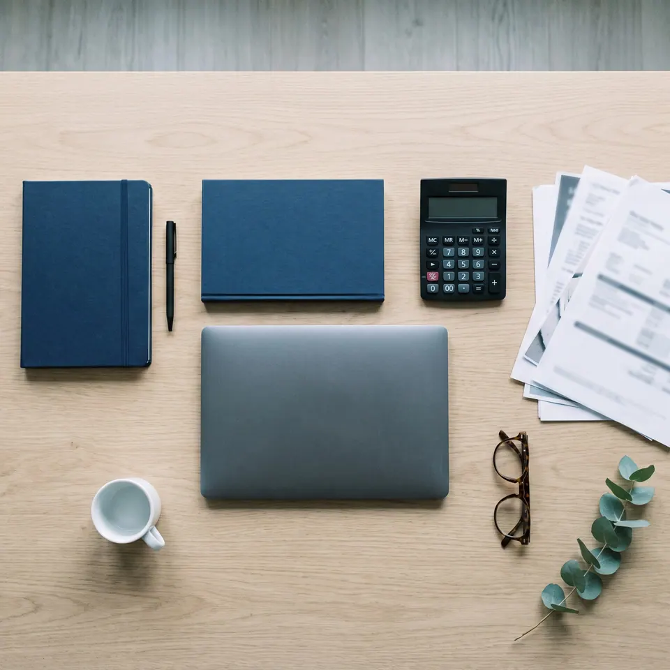 Aufgeräumter Schreibtisch mit Notizbuch, Laptop und Taschenrechner